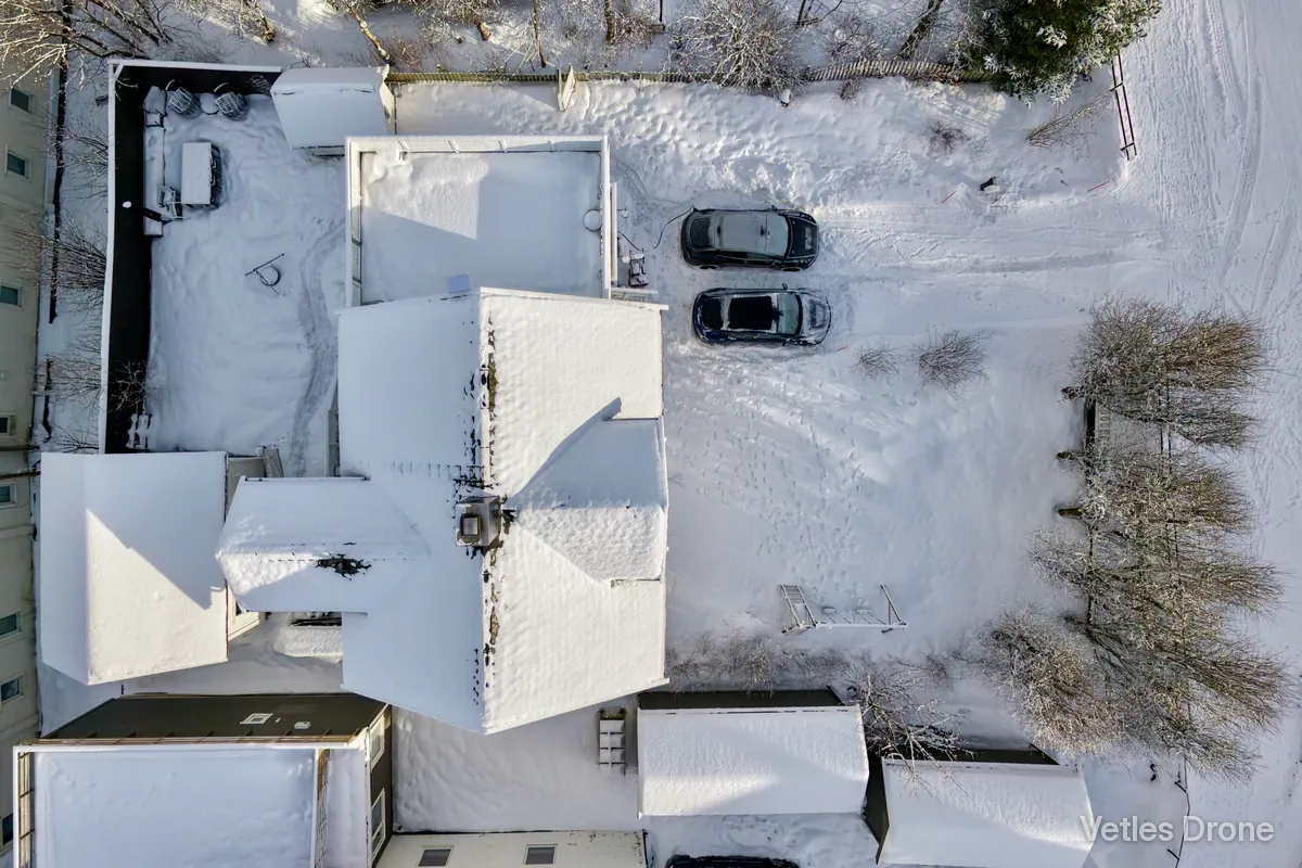 Hus og uthus med tykt snølag på takene etter snøfall, fotografert rett ovenfra med drone